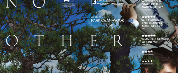 Man holding up a bucket with trees in the background.