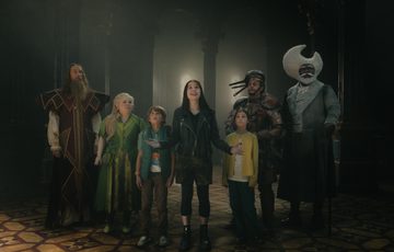 Actors stood together in the middle of a room.