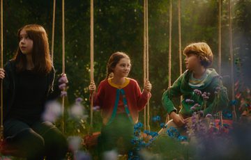 3 children all sat on swings in a forest.