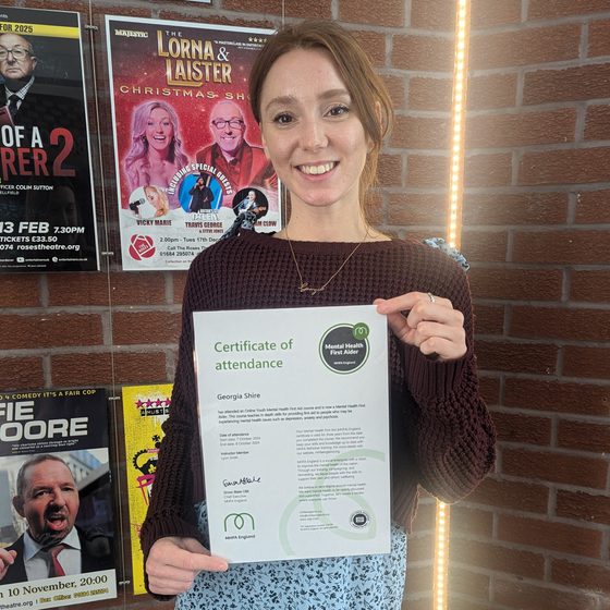 Georgia, CYP Producer, holding up her Mental Health First Aider certificate.