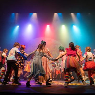RYC children in The Wizard of Oz dancing in a circle on stage.