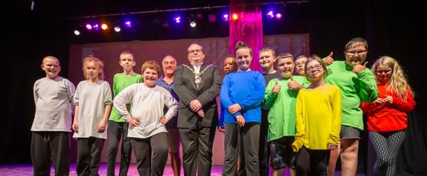 A group of children line up on stage to take a bow after a successful performance