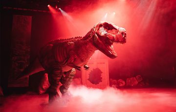 Dinosaur with red lighting and smoke on stage
