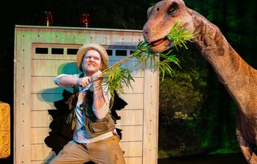 Man feeding dinosaur a branch