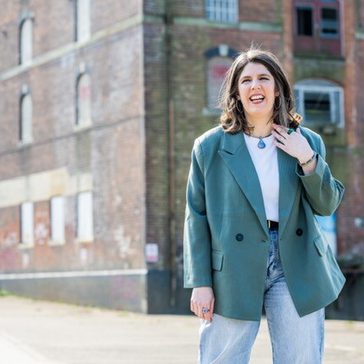 Lindsay standing in front of a building smiling.