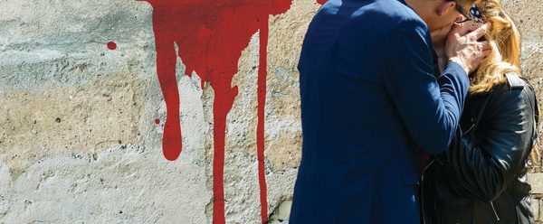 Romeo and Juliet on the wall in the background with 2 people kissing.