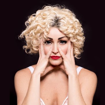 Tasha dressed as Madonna with her hands around her face.