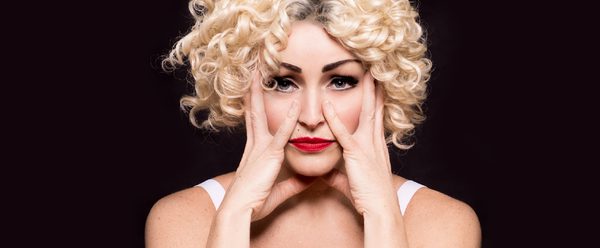 Tasha dressed as Madonna with her hands around her face.