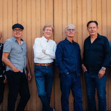 The Manfreds stood along a wall.