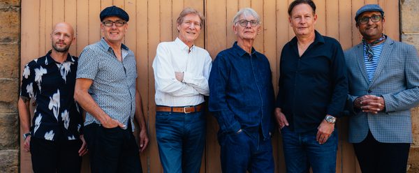 The Manfreds stood along a wall.