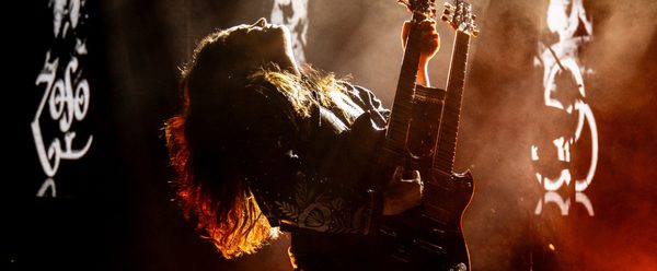 Woman holding a guitar looking upwards.
