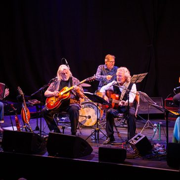 Band sat down playing instruments.