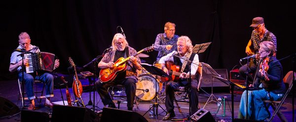 Band sat down playing instruments.