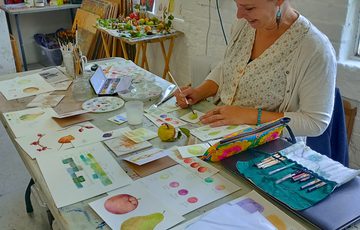 Lady sat down drawing a rose.