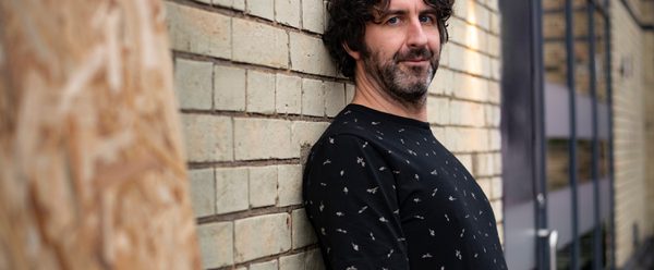 Mark leaning against a wall.