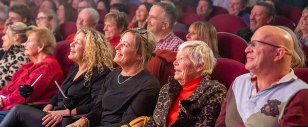 A full auditorium of people laughing and smiling