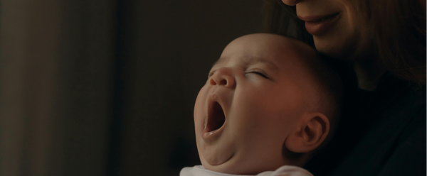 Baby yawning sat on woman.